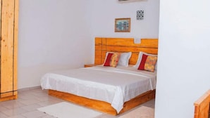 A bedroom with a wooden headboard, a white bedspread, and two pillows.