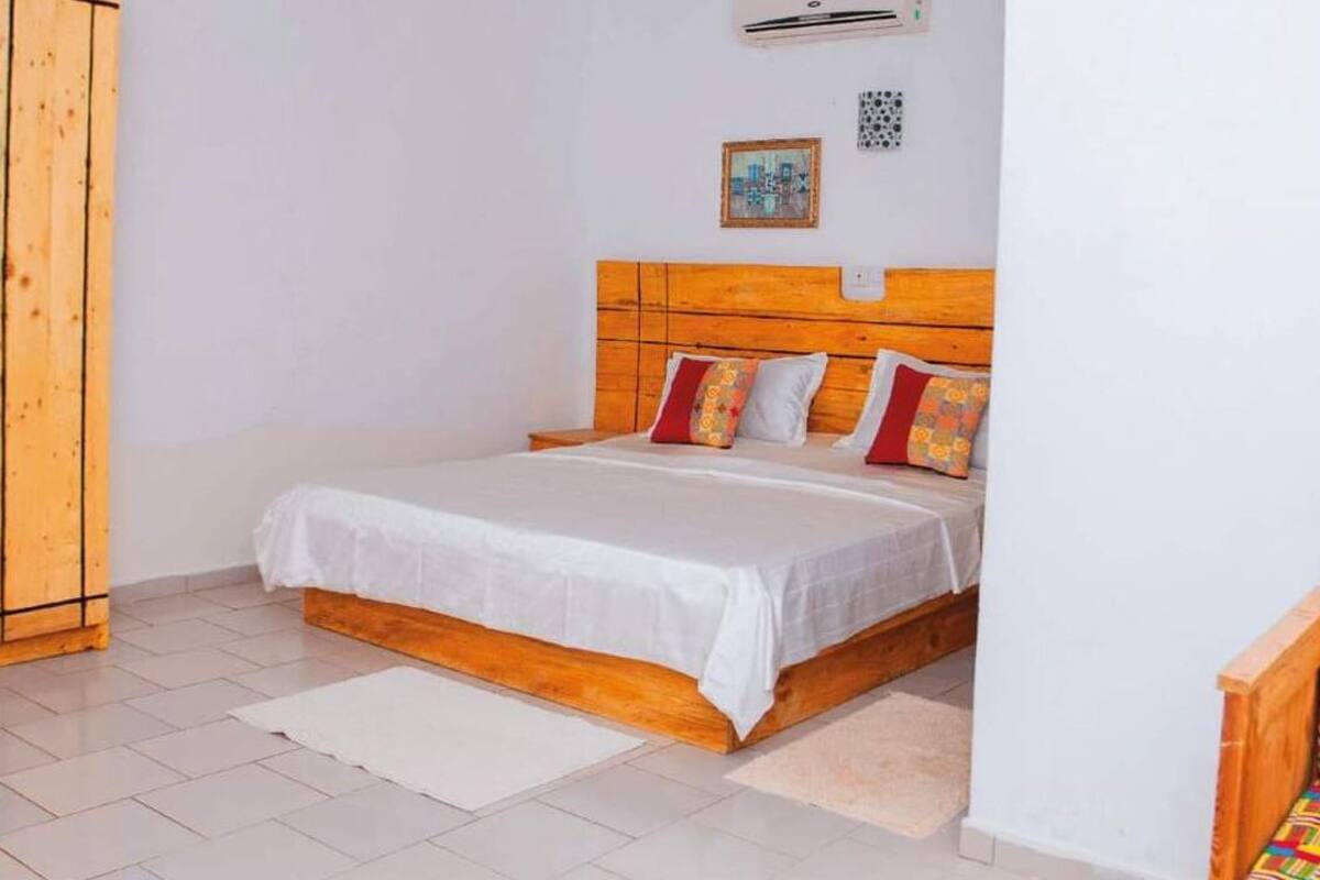 A bedroom with a wooden headboard, a white bedspread, and two pillows.