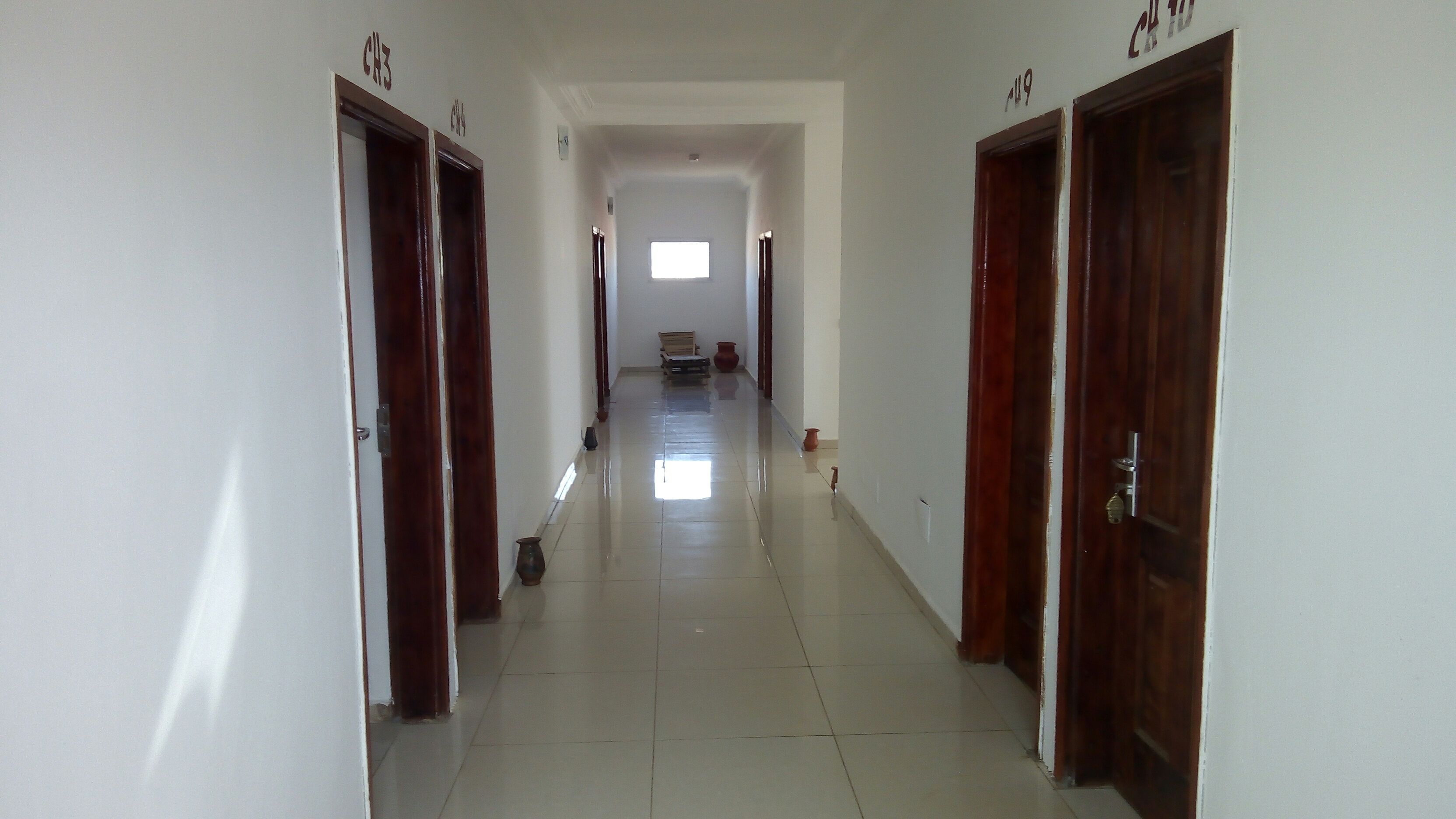 A long, narrow hallway with wooden doors labeled with room numbers.