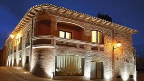 Un edificio de piedra con balcón y ventanas amplias, iluminado con luz cálida.