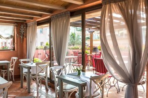A restaurant with outdoor seating, white chairs, and tables. - Sa Calma Hotel (Begur)