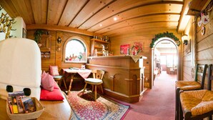 A cozy wooden interior with a sofa, a dining table, and a bar area. - Pension Grubenhof (Fulpmes)