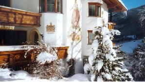 A traditional chalet with a wooden facade, a coat of arms, and a snow-covered landscape. - Pension Grubenhof (Fulpmes)