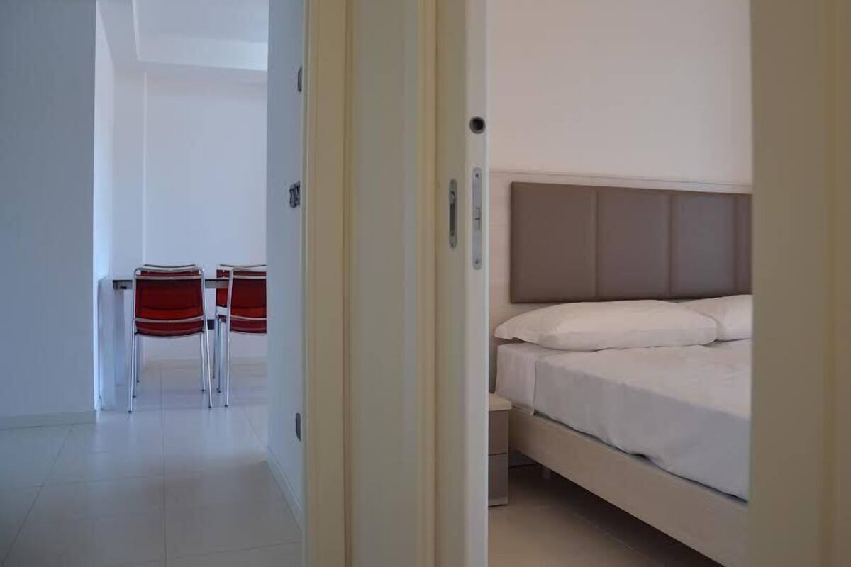 A bedroom with a bed, a nightstand, and a chair.