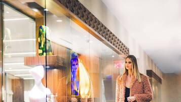 A modern interior with a glass storefront, a mannequin, and a person standing.