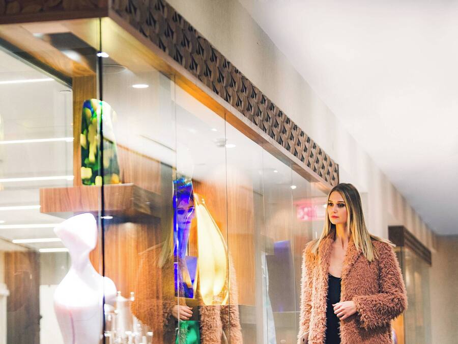 A modern interior with a glass storefront, a mannequin, and a person standing.