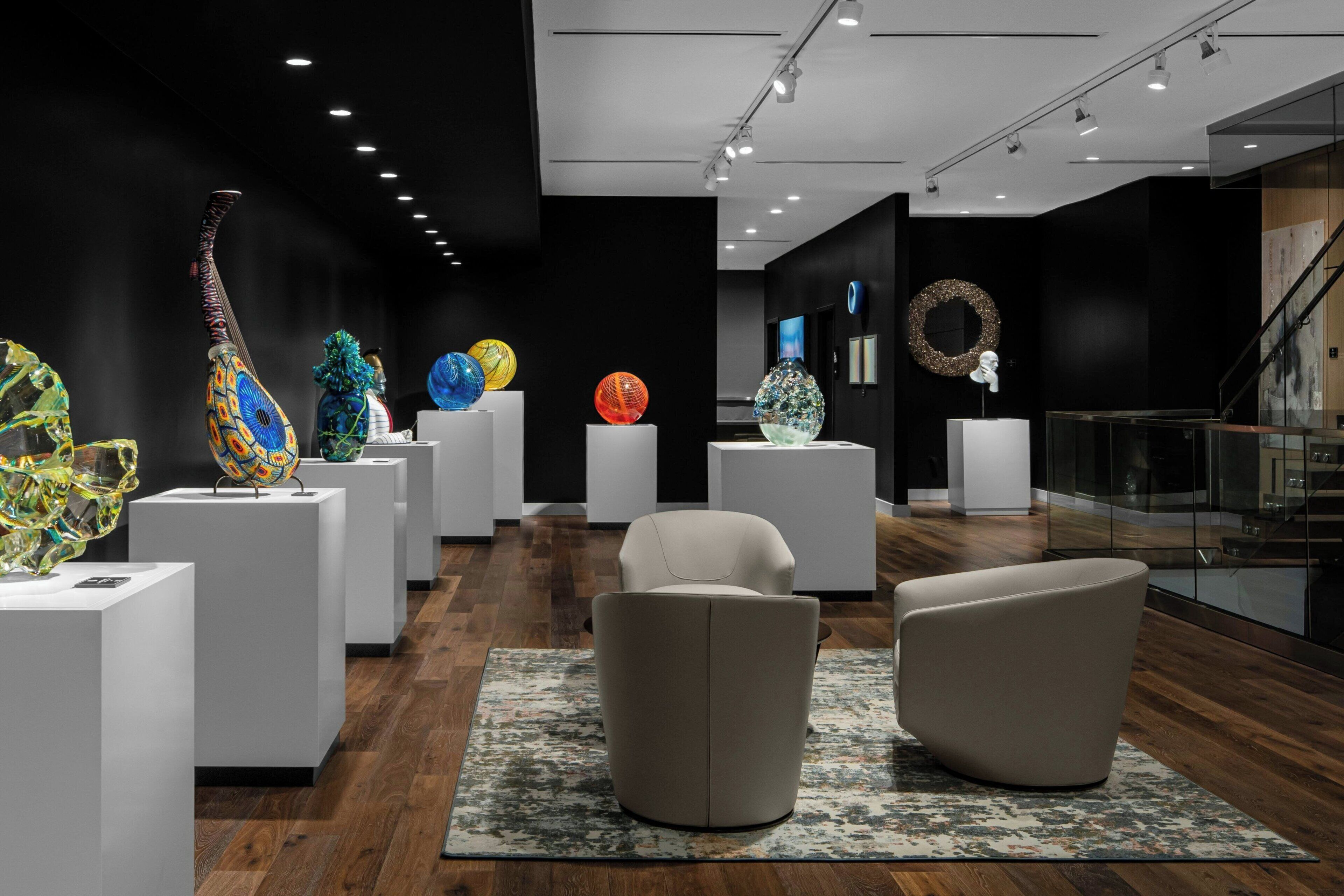 Une galerie d’art moderne où sont exposées des sculptures abstraites, avec un escalier et des espaces de détente au design contemporain.