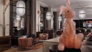 Un intérieur moderne agrémenté d’une grande sculpture de lapin rose, de meubles contemporains et d’appareils d’éclairage élégants.