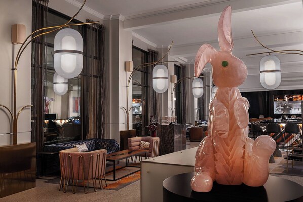 A modern interior with a large pink bunny sculpture, contemporary furniture, and stylish lighting fixtures.