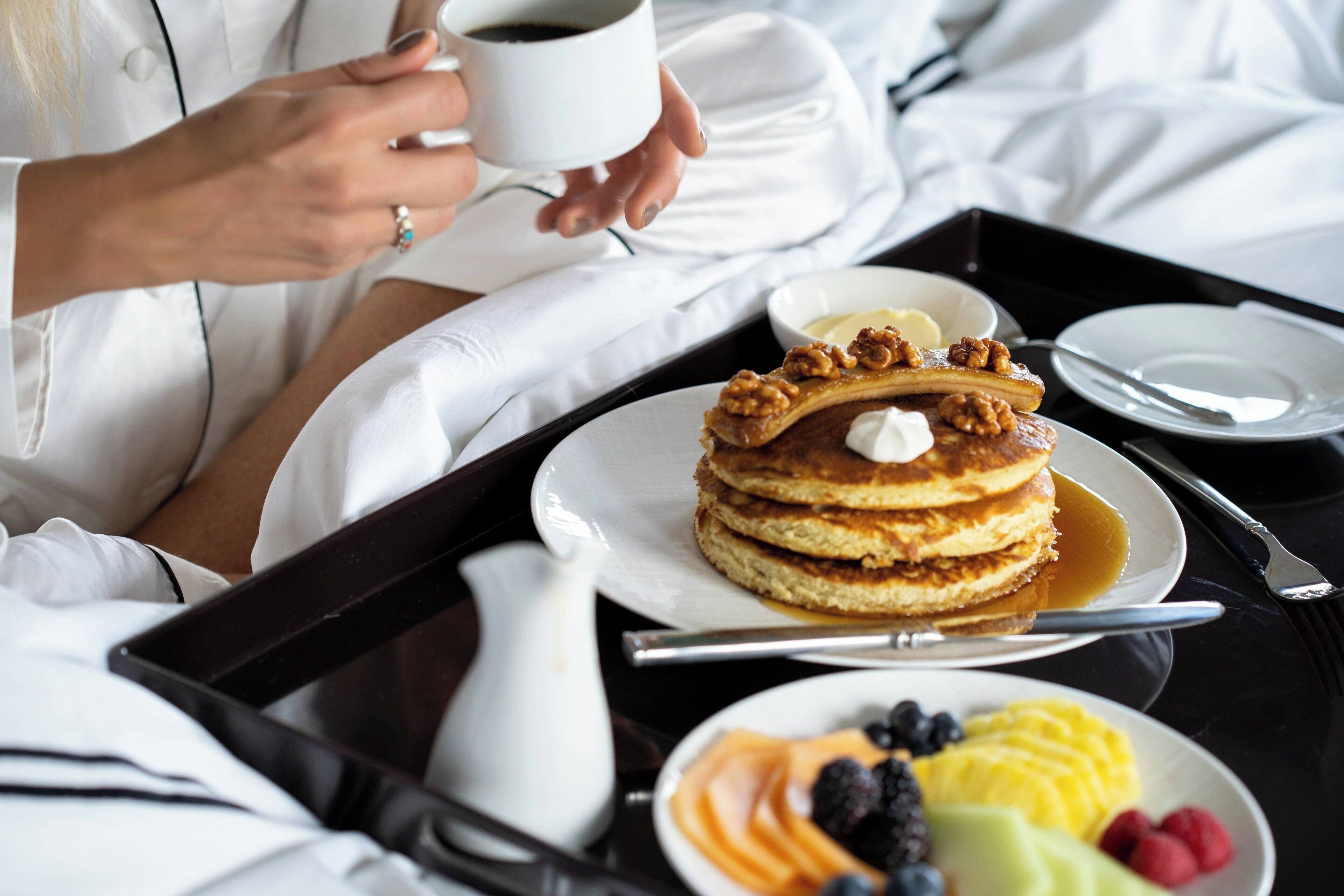Ein Frühstücksbrett mit Pfannkuchen, Ahornsirup, einem Milchbehälter und einer Obstplatte.