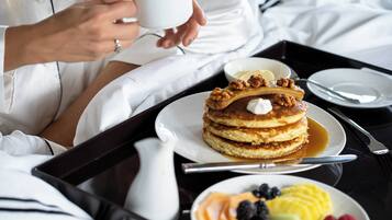 Ein Frühstücksbrett mit Pfannkuchen, Ahornsirup, einem Milchbehälter und einer Obstplatte.