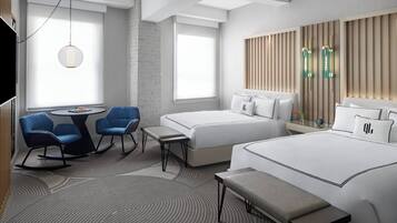 A modern hotel room with a large bed, two smaller beds, a desk with chairs, and a seating area with a bench.