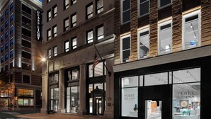 La façade d’un hôtel, avec une grande entrée, un drapeau et une devanture portant l’inscription « Perry Glass Art Collection ».