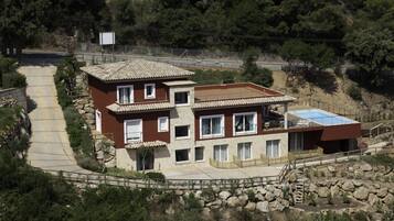 Una casa de dues plantes amb façana de pedra, teulada de teules i un balcó.