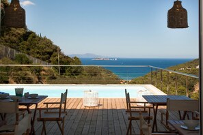 A wooden deck with a pool, overlooking a coastal landscape with a view of the sea and distant islands. - Es Cel de Begur Hotel (Begur)