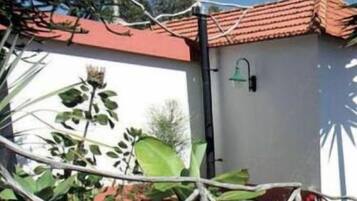 Een wit gebouw met een rode pannendak, een zwarte pijp en een groene lamp.