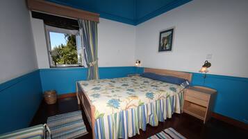 Une chambre à coucher avec un lit, des tables de chevet, une fenêtre avec des rideaux, une commode et un tableau au mur.