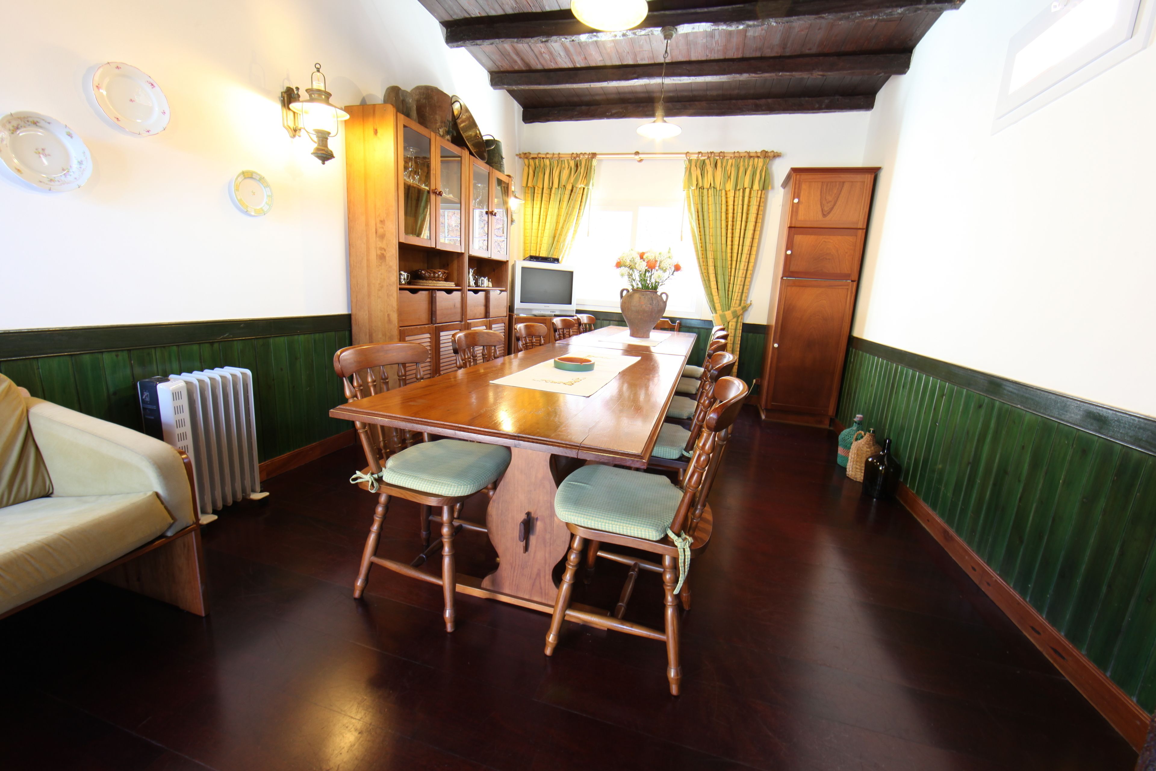 A dining area with a wooden table and chairs, a sofa, and a radiator.