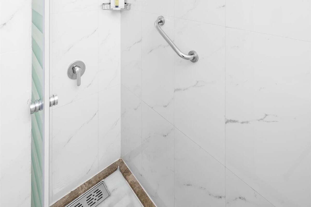 A modern shower with a handheld showerhead, a handheld shower bar, and a control panel.