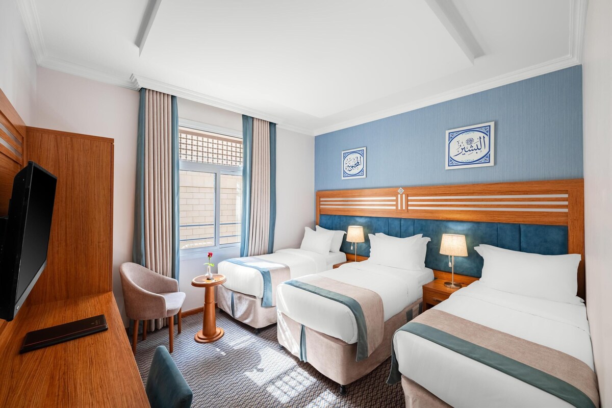 Habitación de hotel con dos camas, un televisor, un escritorio y una silla.
