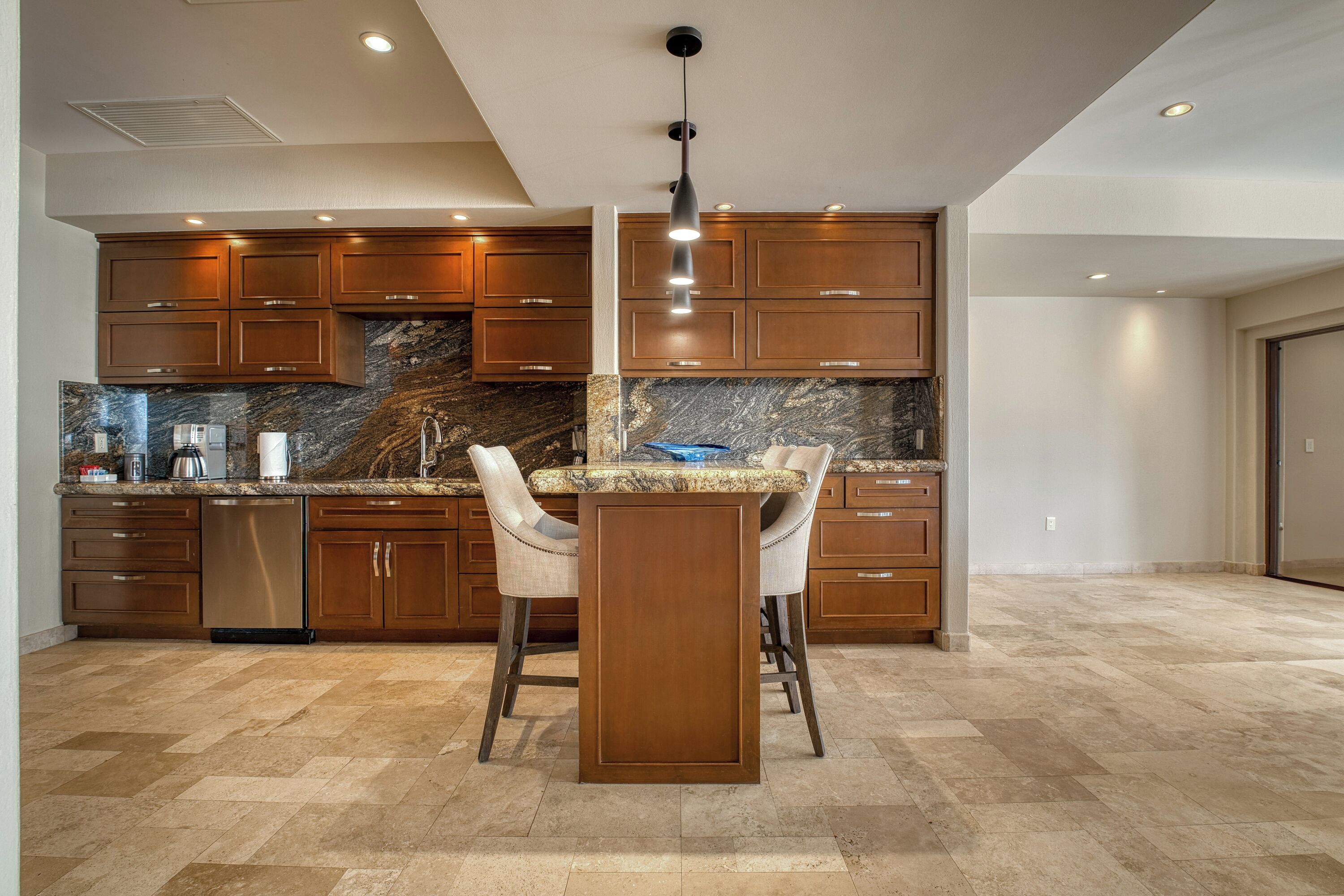 A modern kitchen with dark wooden cabinets, a granite countertop, and a central island with bar stools.