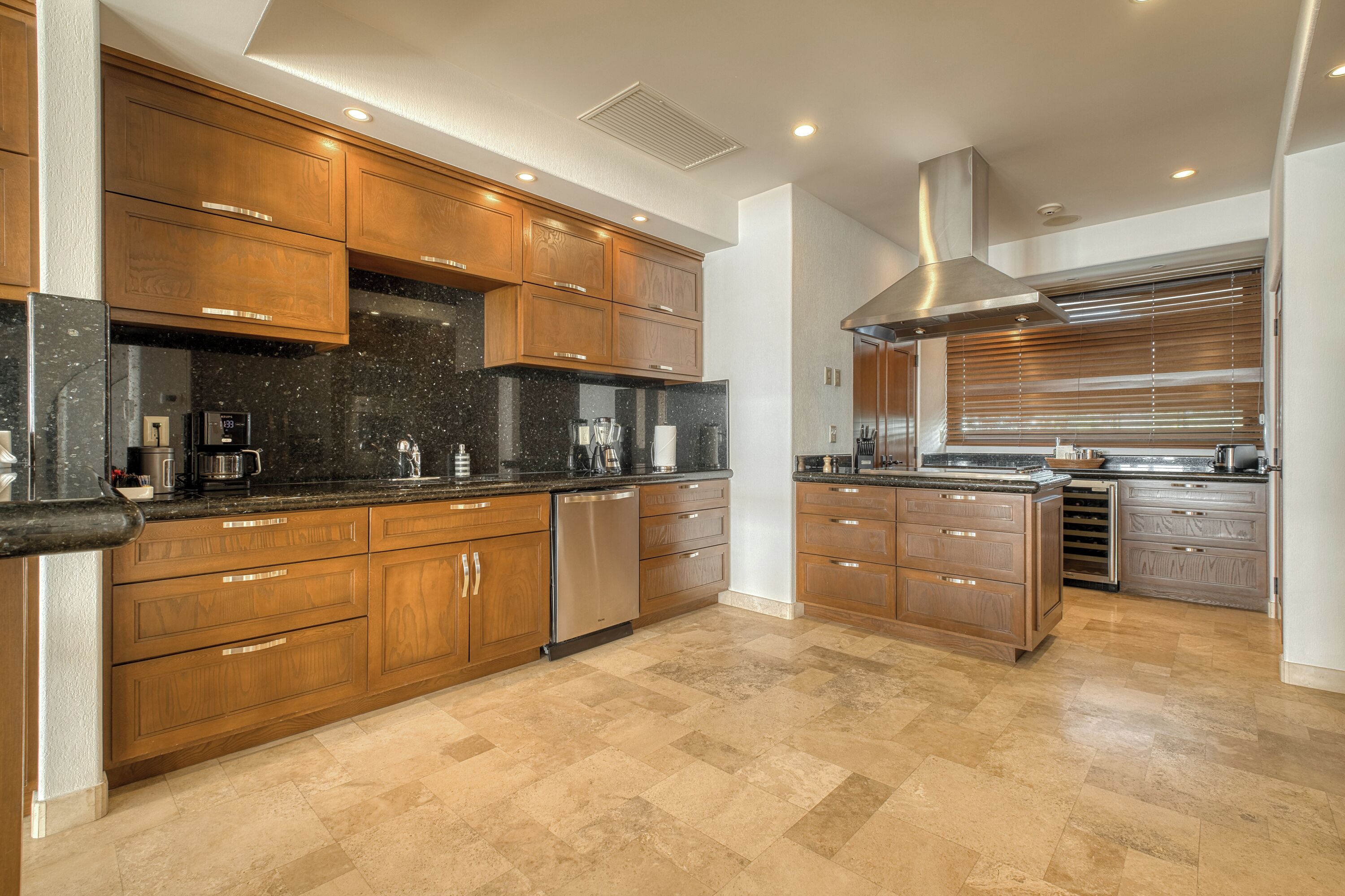 A modern kitchen with wooden cabinets, stainless steel appliances, and a large island.