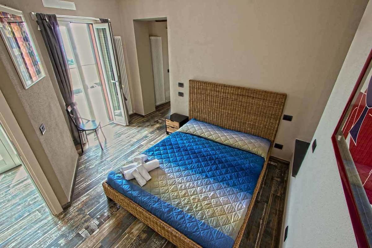 A room with a bed, a chair, and a door leading to a balcony.