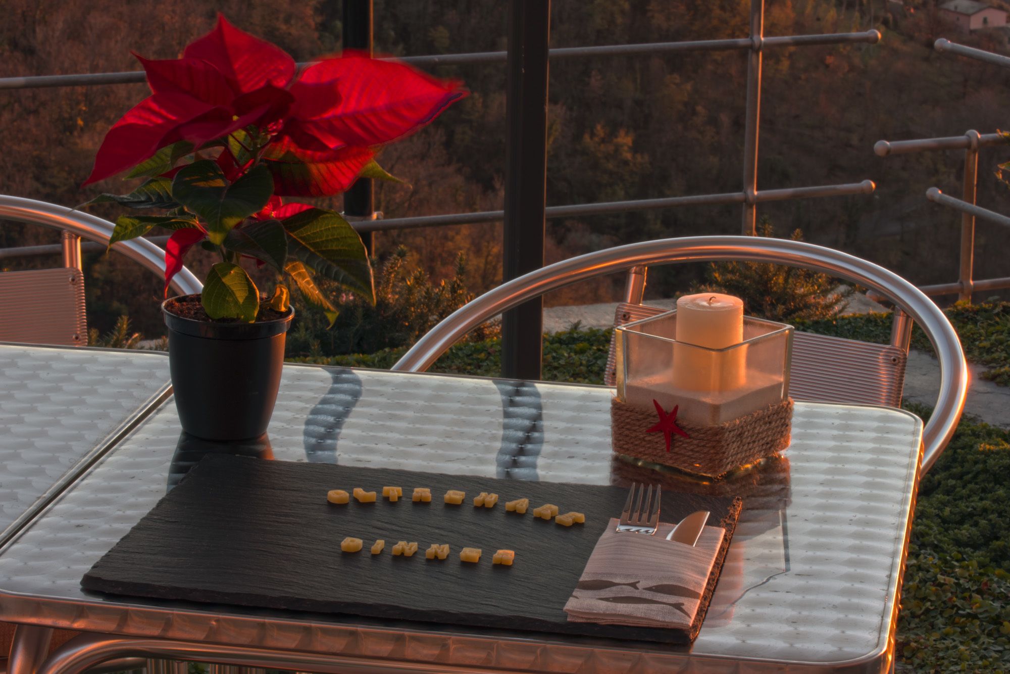 A table with a potted plant, a candle, and some food items.