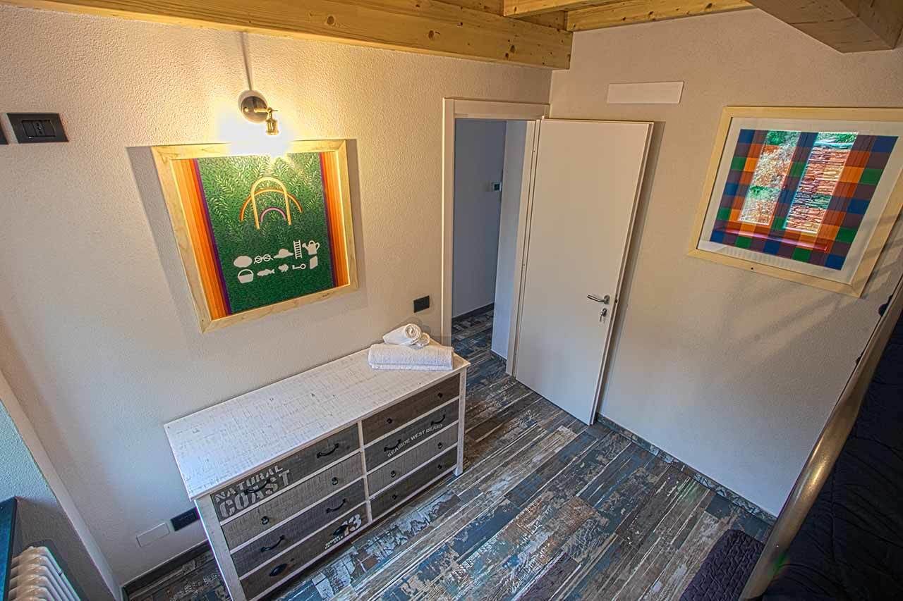 En hall med en träbänk, en inramad tavla på väggen och en dörr som leder till ett annat rum.