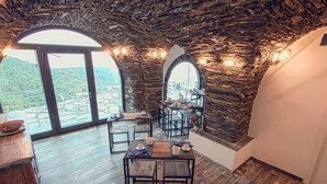 A rustic interior with stone walls, wooden flooring, and tables set for dining. - Oltremare Guest House (Lavagna)