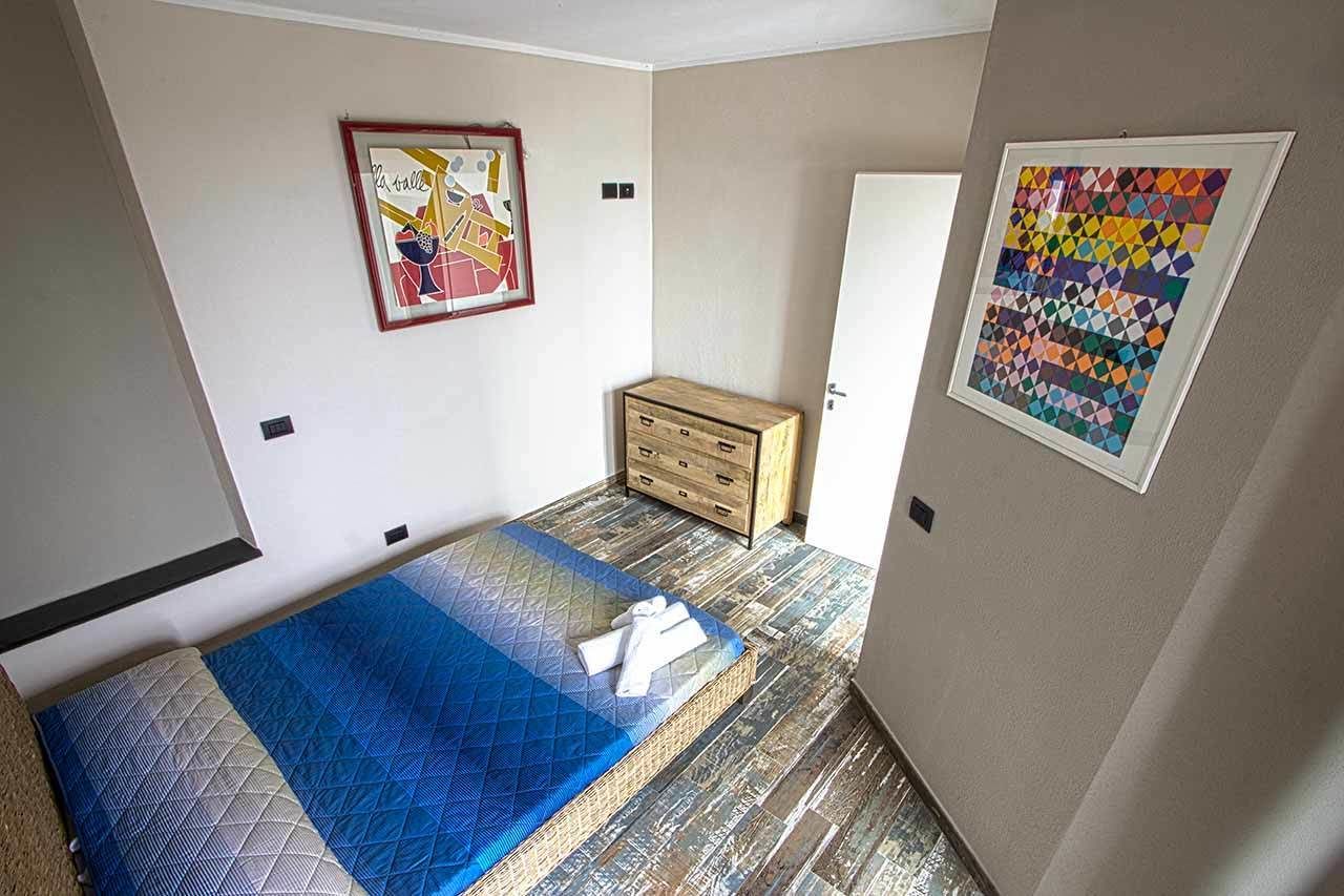 A bedroom with a bed, a dresser, and two framed artworks on the walls.