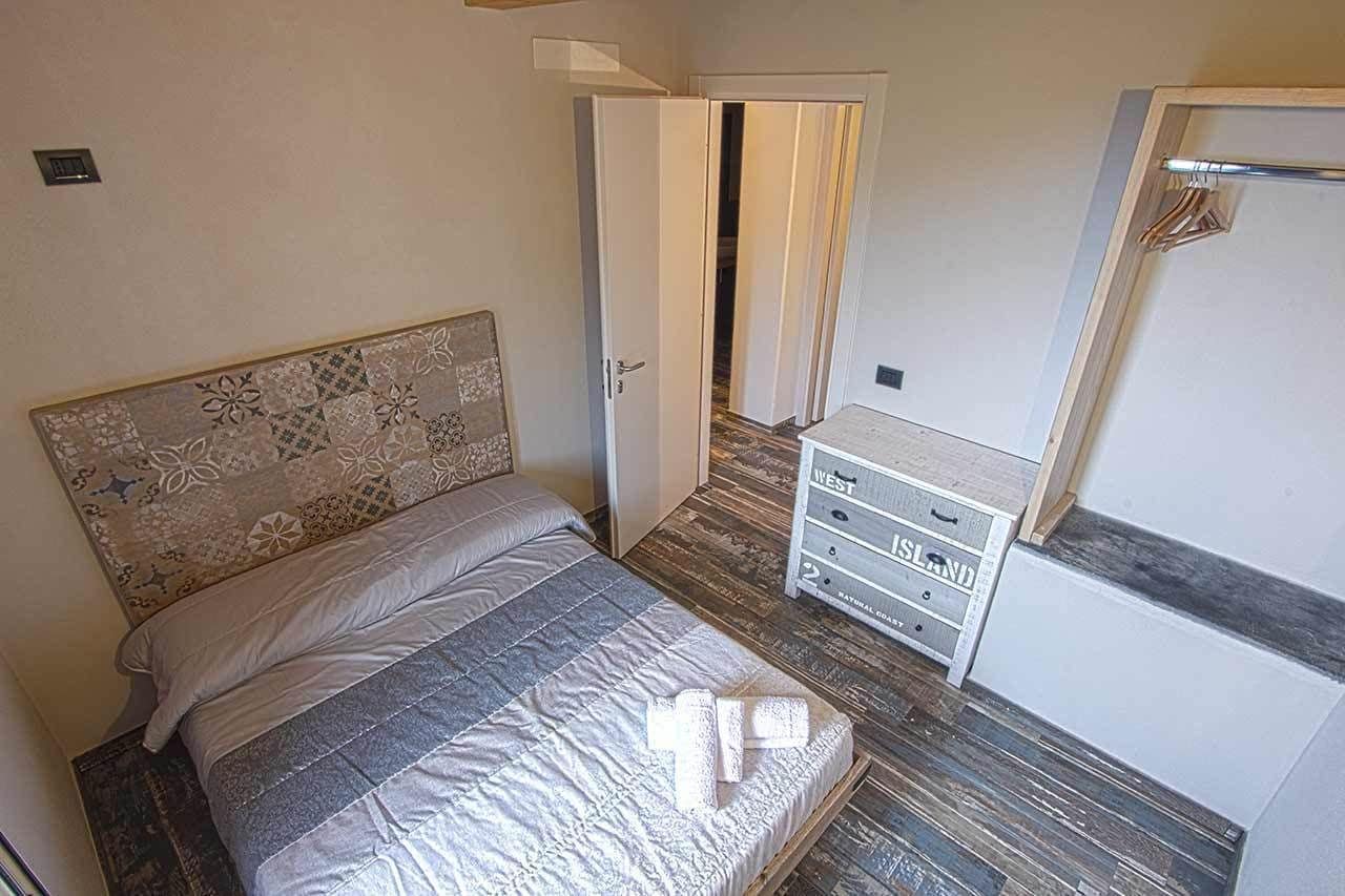 Un dormitorio con una cama, un aparador y una puerta que da a otra habitación.