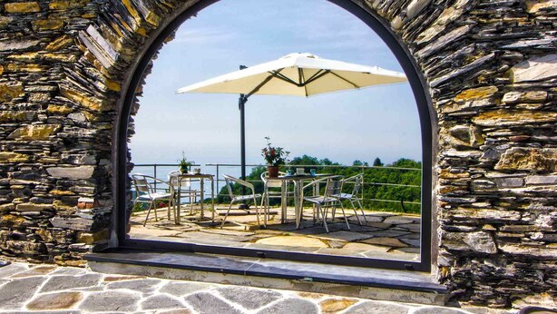 An outdoor patio with stone walls, a table, chairs, and an umbrella. - Oltremare Guest House (Lavagna)