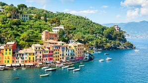 A coastal town with colorful buildings, boats in the water, and a hilly backdrop. - Oltremare Guest House (Lavagna)