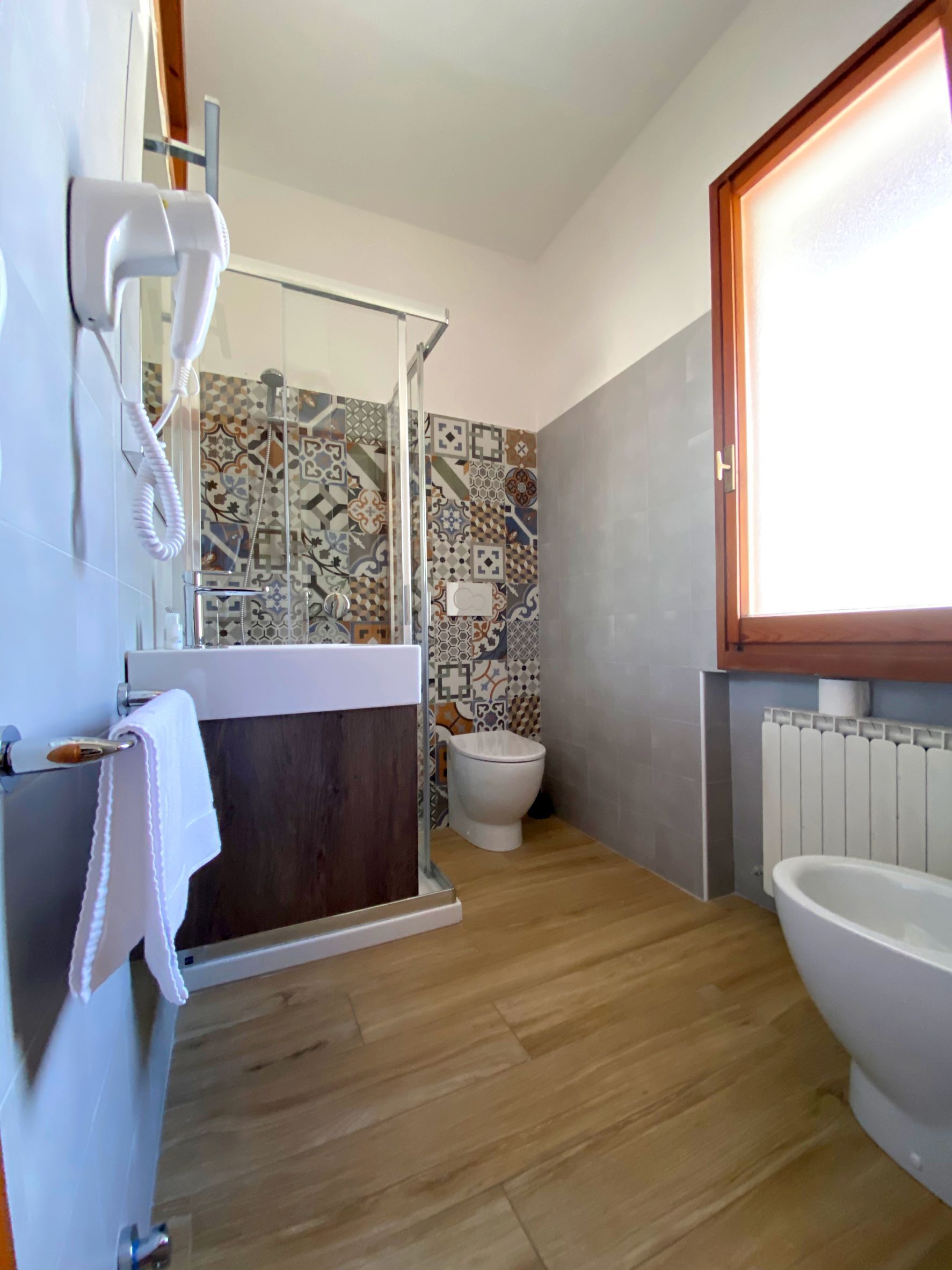 Un baño con ducha, inodoro y lavamanos, con una toalla colgada en la pared.
