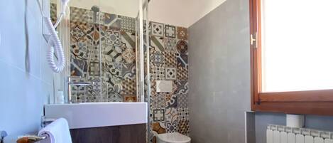 Un baño con ducha, inodoro y lavamanos, con una toalla colgada en la pared.