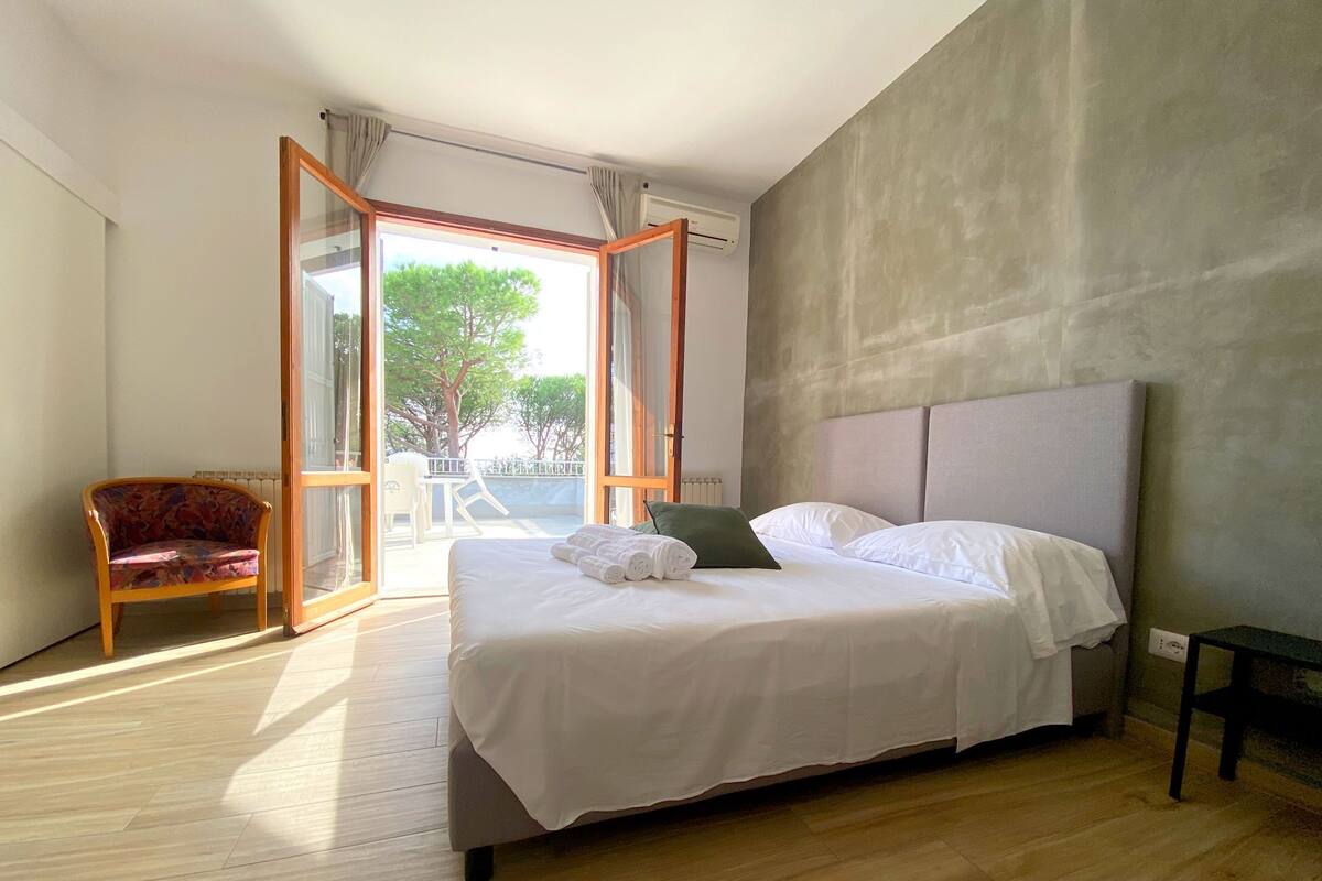 A bedroom with a bed, a chair, and a view of the outdoors.