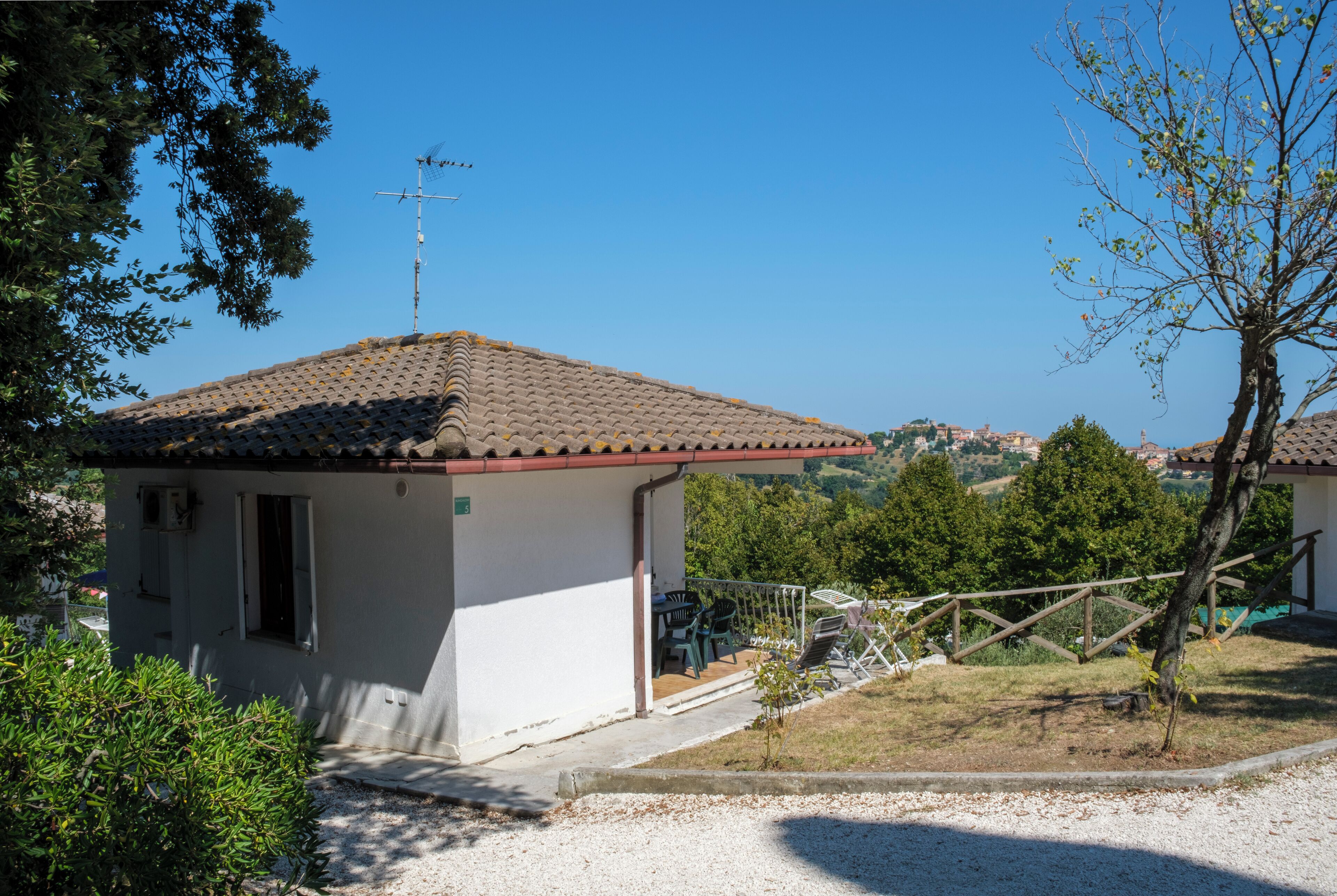 Un petit bâtiment d’un seul étage, doté d’un toit en tuiles, d’un balcon et offrant une vue sur un paysage vallonné.