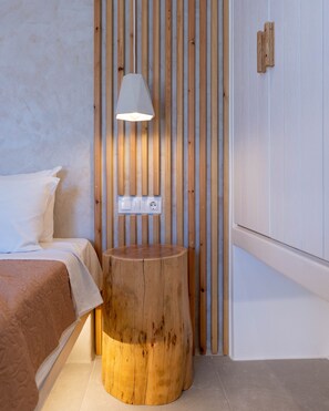A bedroom with a wooden nightstand, a bed with white bedding, and a wall-mounted light fixture. - Dedalos Studios Naxos (Naxos)