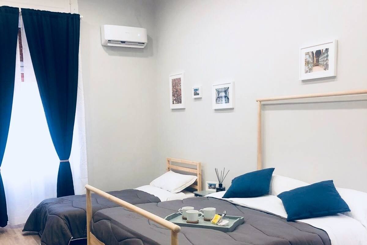 A modern hotel room with a wooden bed, a small yellow chair, and a tray with cups and a book.