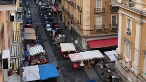 A street view with multi-story buildings, outdoor markets, and parked cars. - Palazzo Ferrara (Naples)