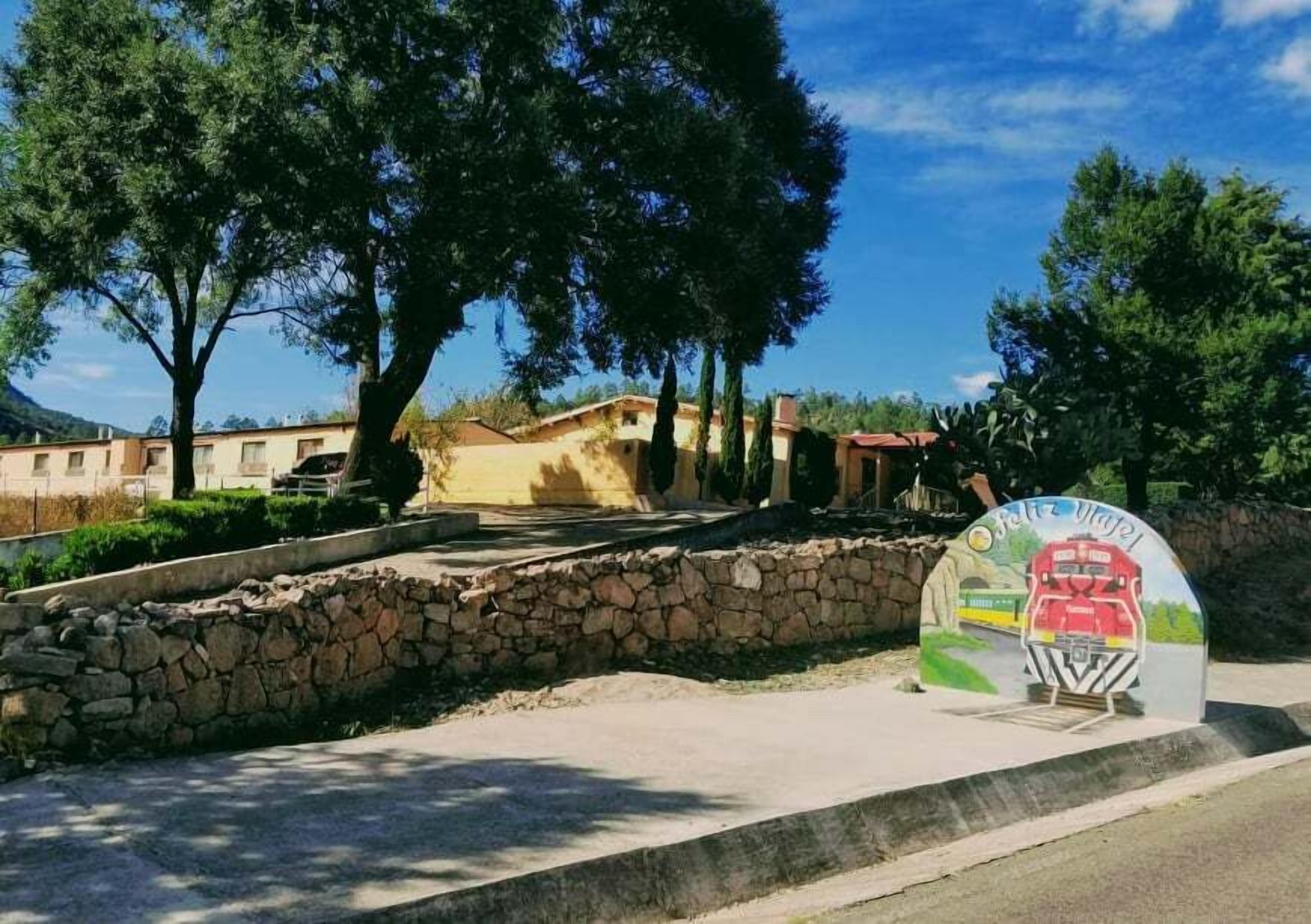 A stone wall, a paved area, and a colorful sign with a train illustration.