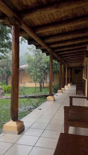 A covered outdoor area with tiled flooring and wooden benches. - Hotel Paraiso del Oso (Urique)