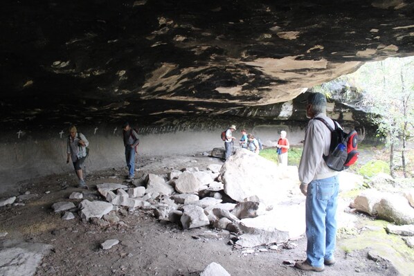 A cave entrance with large rocks and a group of people exploring.