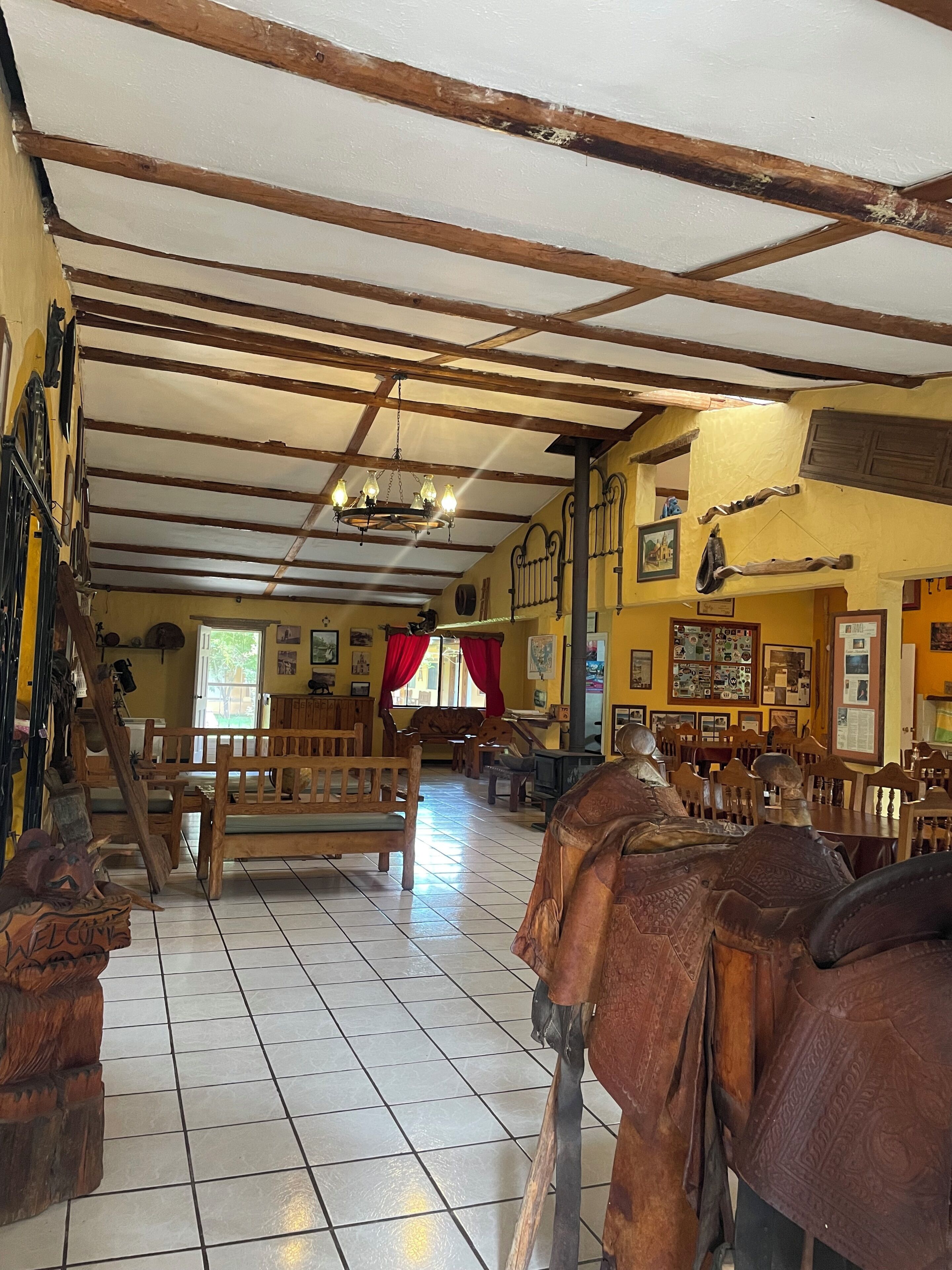 Amplia habitación con vigas de madera, un candelabro y un banco.