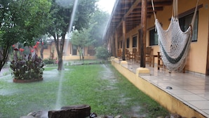 A courtyard with a water feature, a hammock, and a building with a tiled floor. - Hotel Paraiso del Oso (Urique)