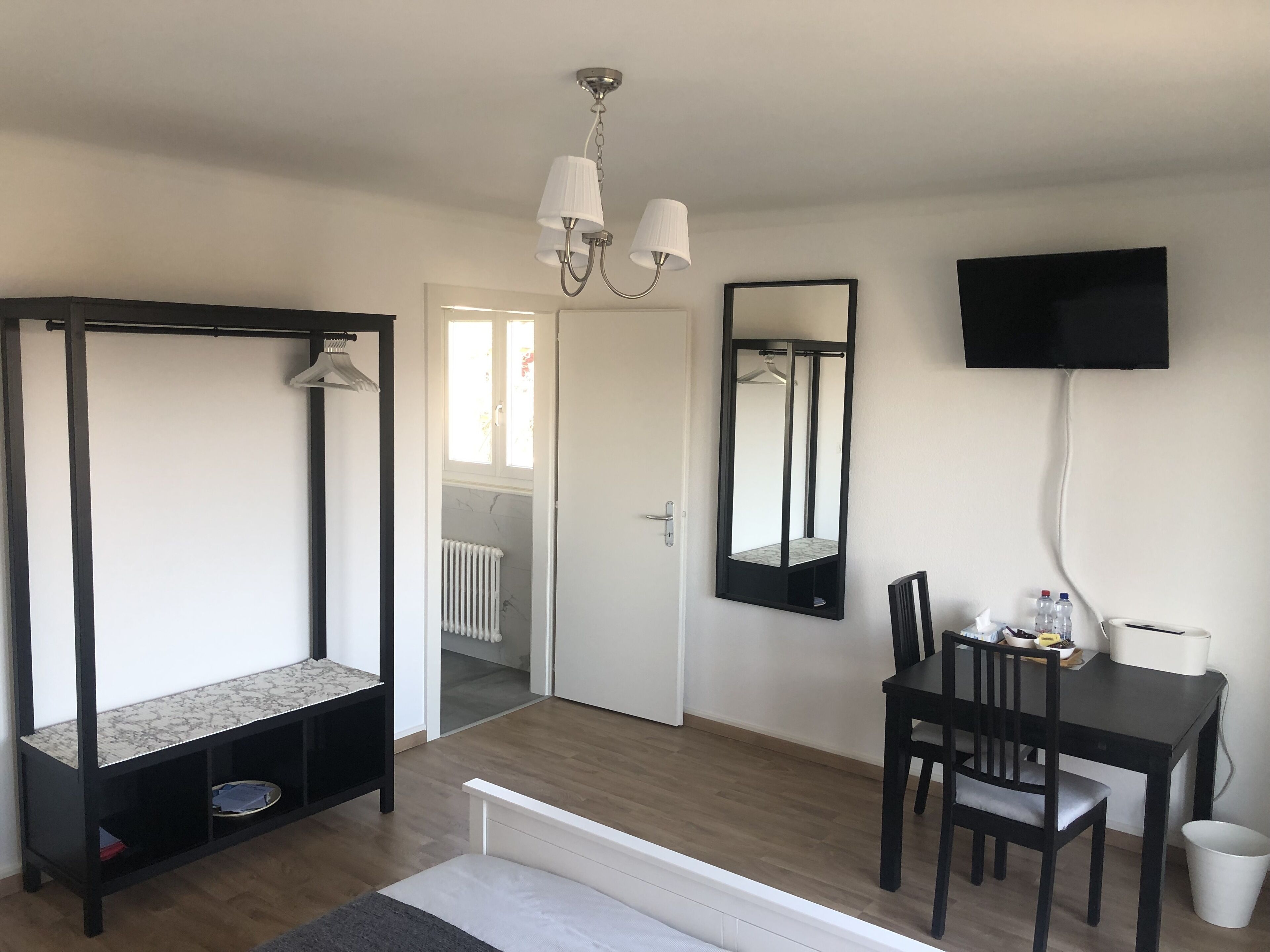 Une chambre avec un lit, un bureau, une chaise, un téléviseur et un radiateur.