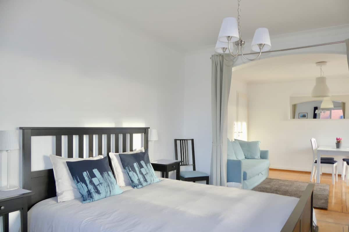 Un dormitorio moderno con una cama grande, mesitas de noche, un escritorio y una silla.
