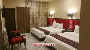 A hotel room with two beds, a chair, a wardrobe, and a curtain. - GreyVillas (Murree)