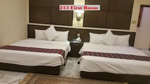 A 215 First Room with two beds, a nightstand, a lamp, and a patterned rug. - GreyVillas (Murree)